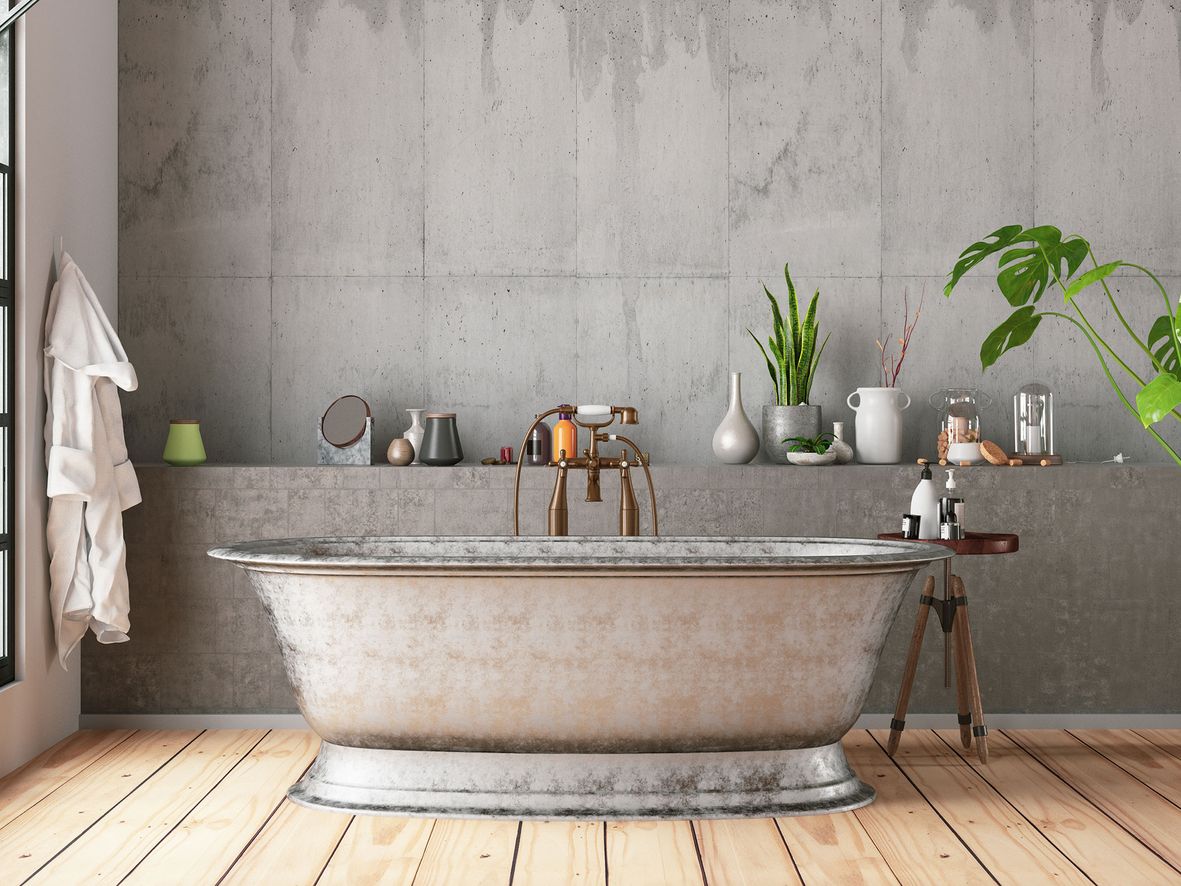 Grey bathroom with concrete walls, a stainless steel bath and wooden floor