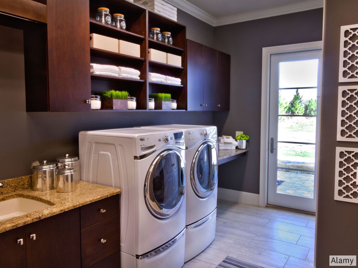 Dark wood units and storage give an eye-catching contrast to white appliances. Think of installing a shelf or worktop at waist height for fluffing and folding laundry before you put it away.