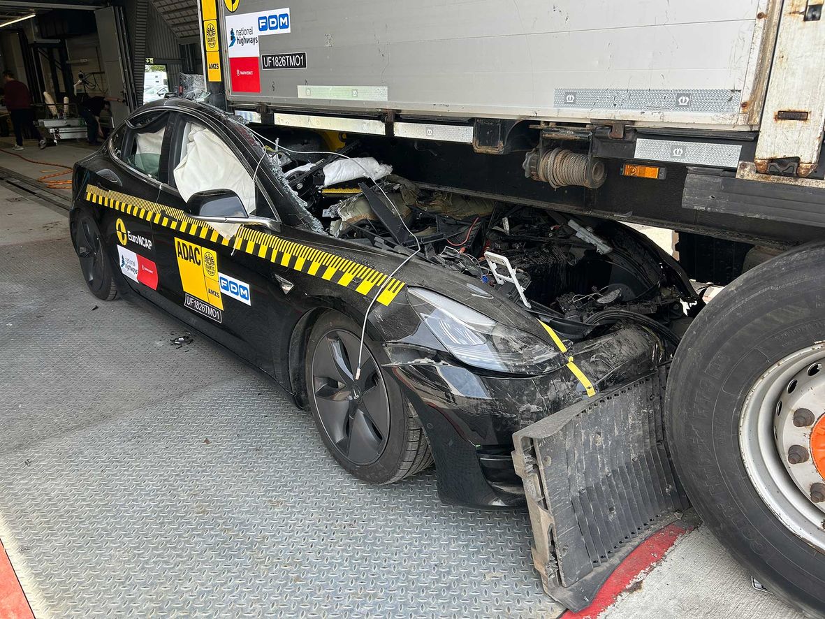 The aftermath of a full-frontal crash test against a European truck trailer. The entire car's passenger compartment is crushed.