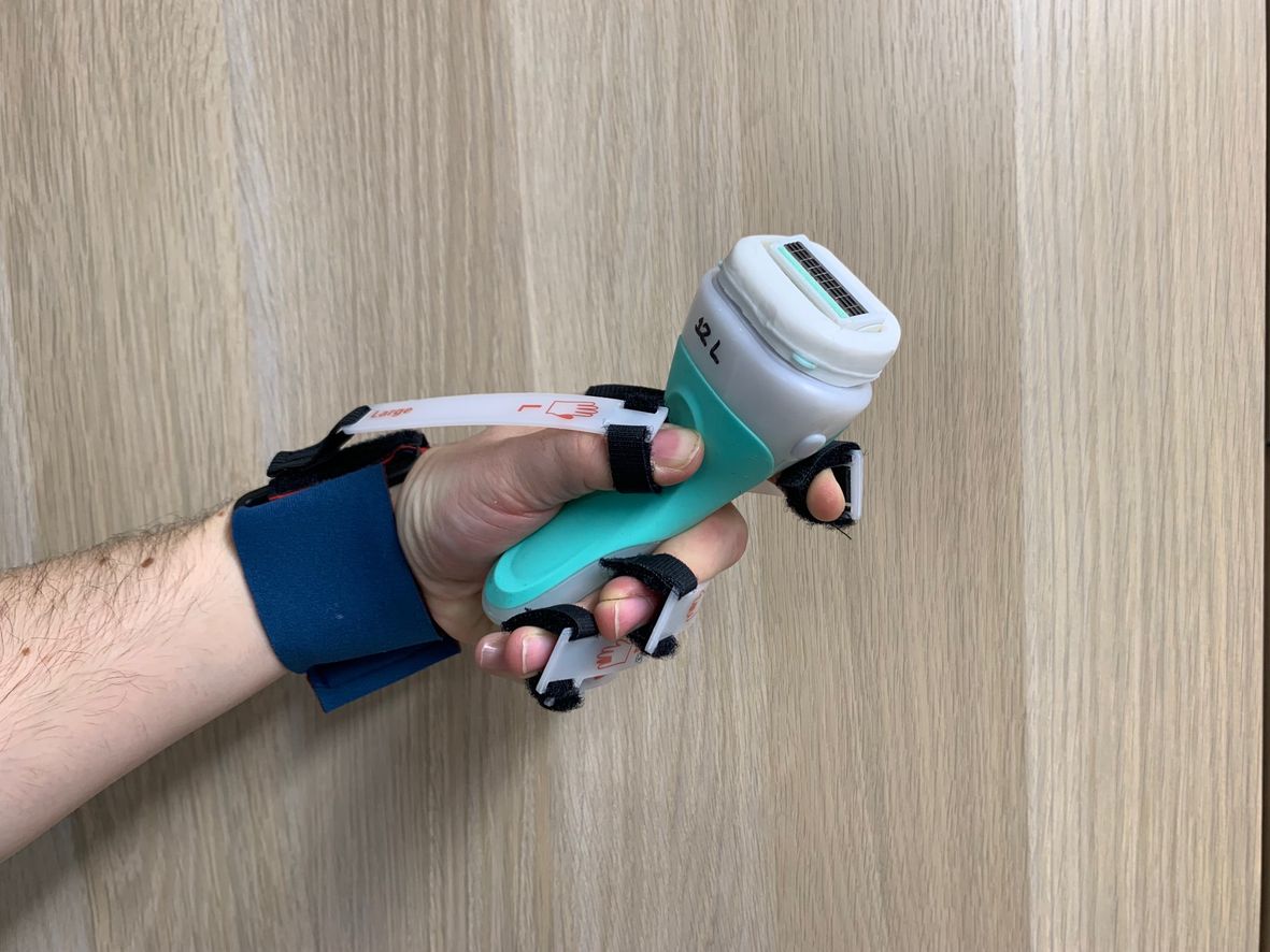 Green women's razor being held in hand wearing the Cambridge Glove to simulate reduced hand strength