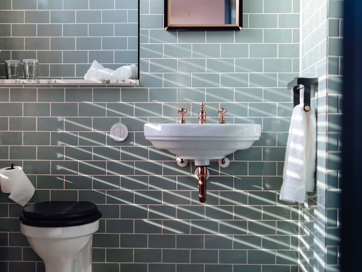 small bathroom with green tiles and a large mirror