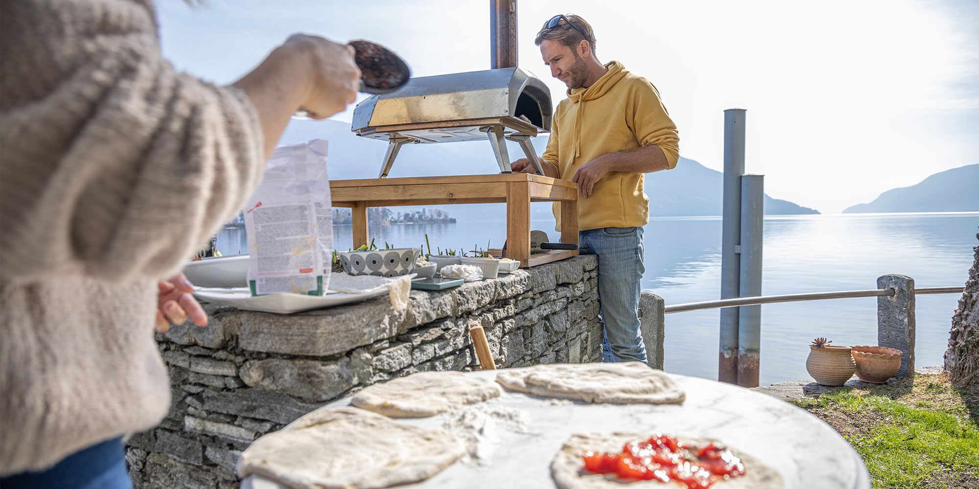 Two people making pizzas outdoors