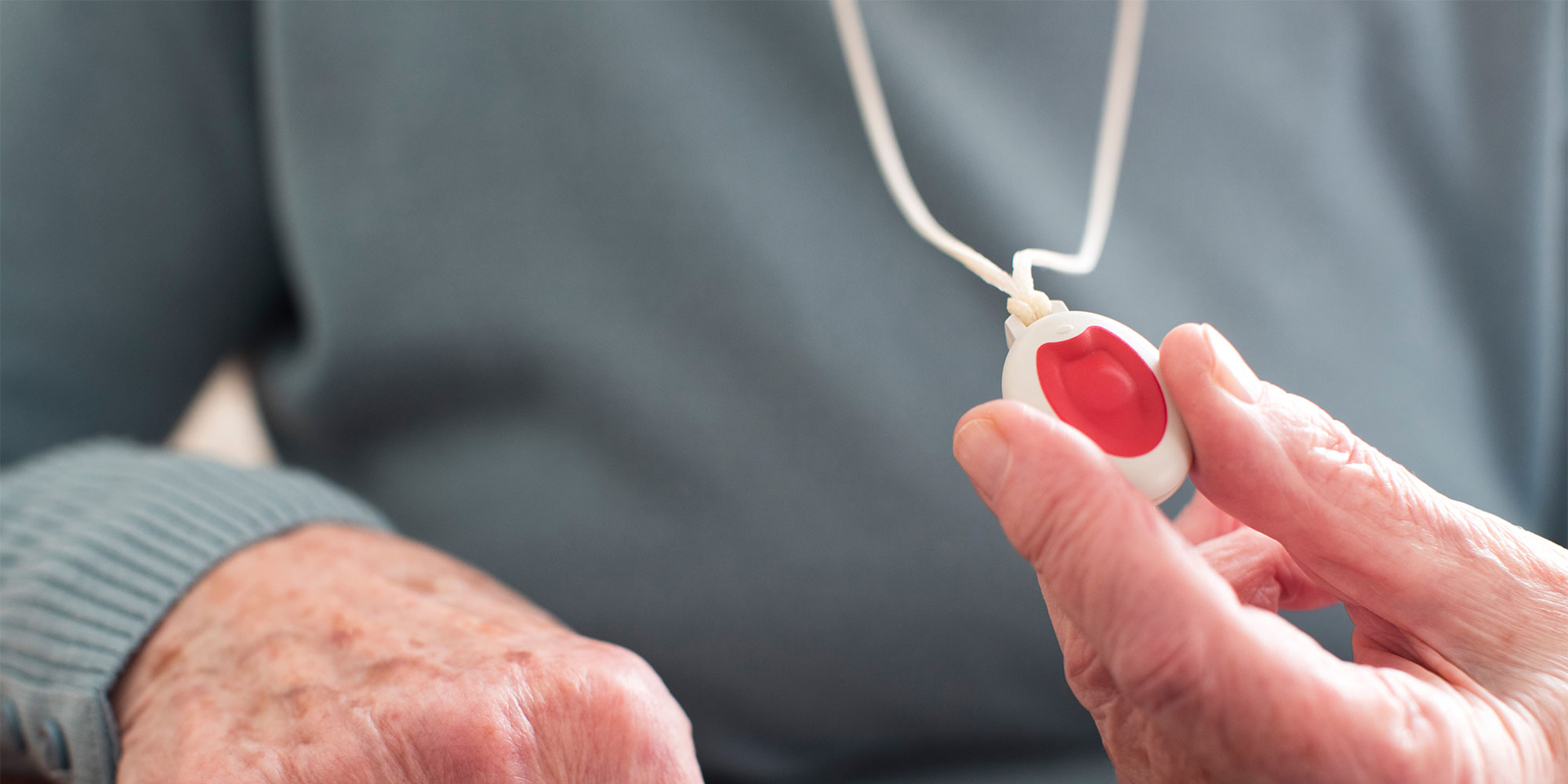 A person holding a GPS pendant alarm