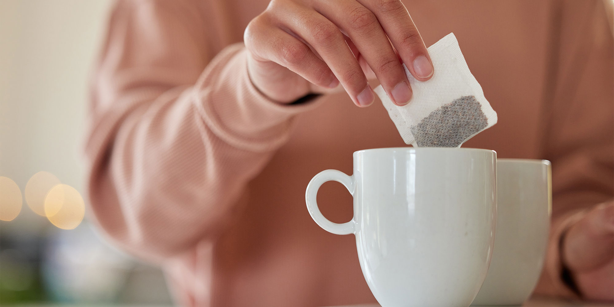 Person putting a teabag into a mug
