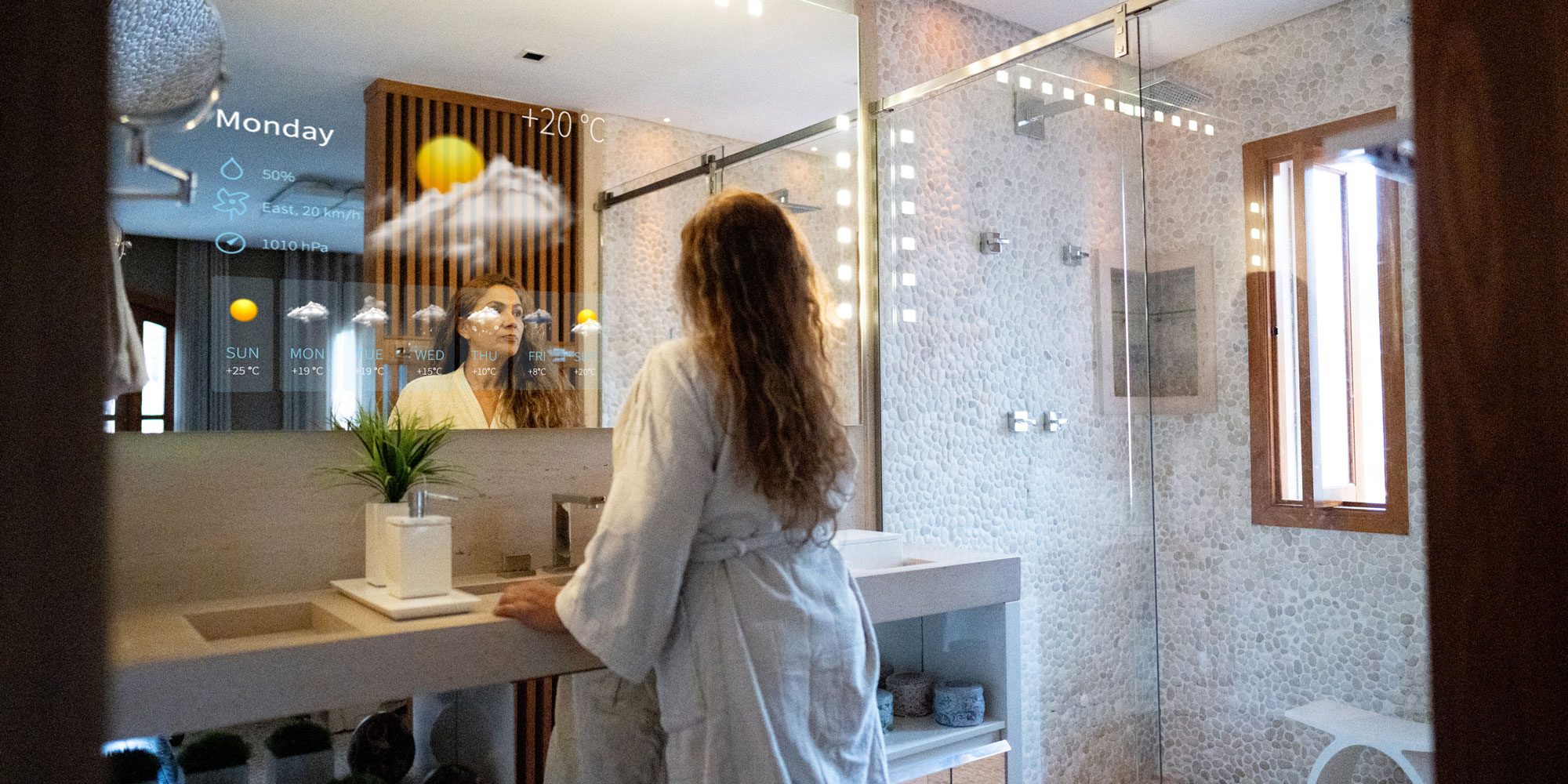 a woman looking at a smart bathroom mirror showing the weather