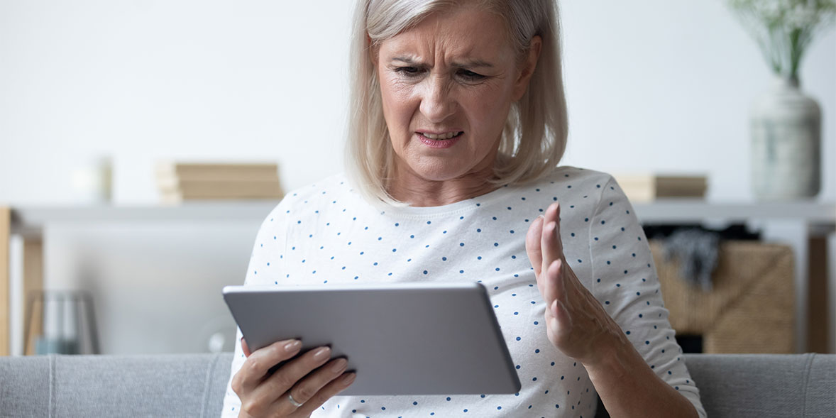 Woman in a white blouse frustrated while using a tablet