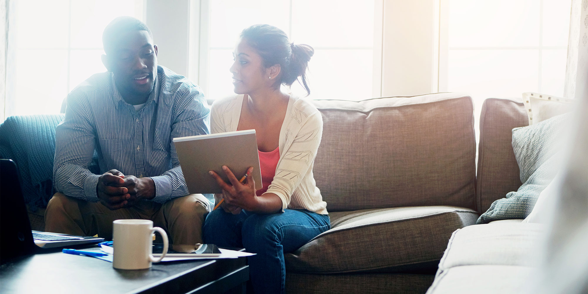 A man and woman sitting on a sofa ticking items off a list