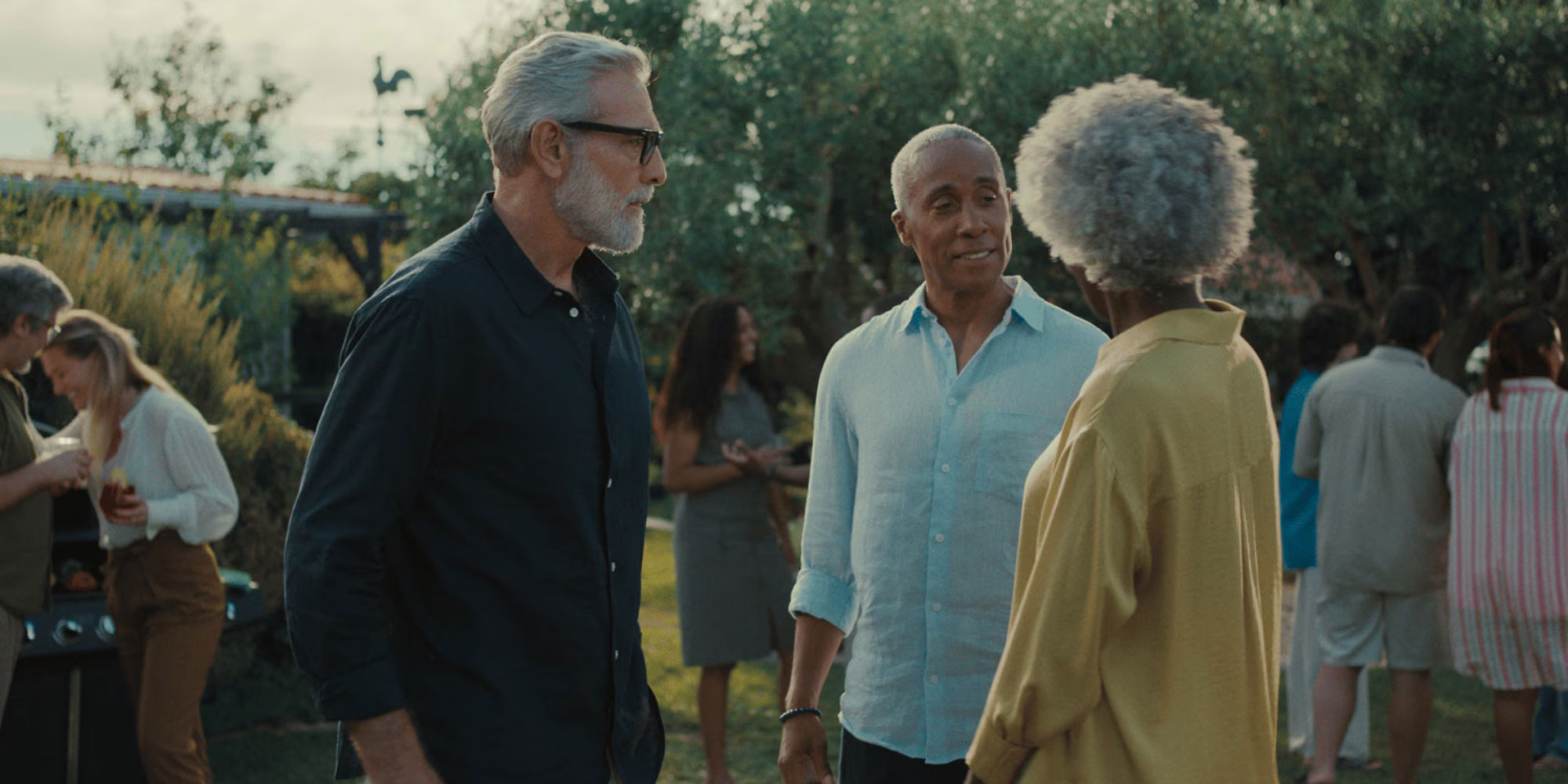 Hearing aid glasses wearer at a social event in conversation 2 men and a woman 