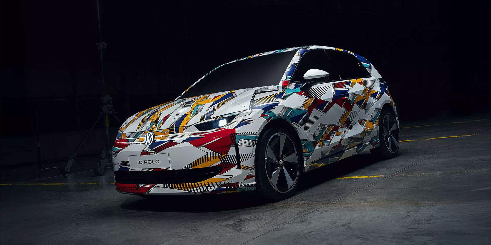 A camouflaged Volkswagen ID. Polo, against a black backgroud