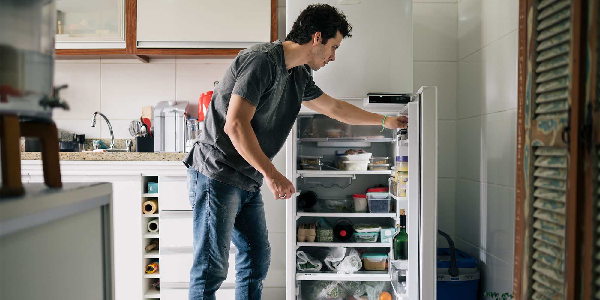 Man arranging food in a fridge freezer