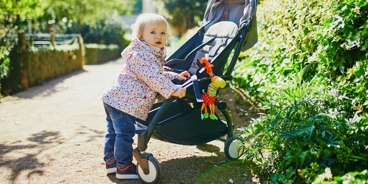 A toddler next to a pram