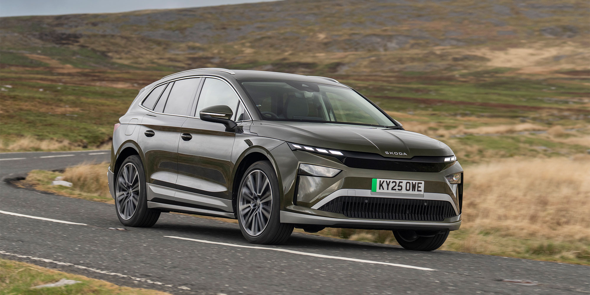 A green Skoda Enyaq, driving on a country road
