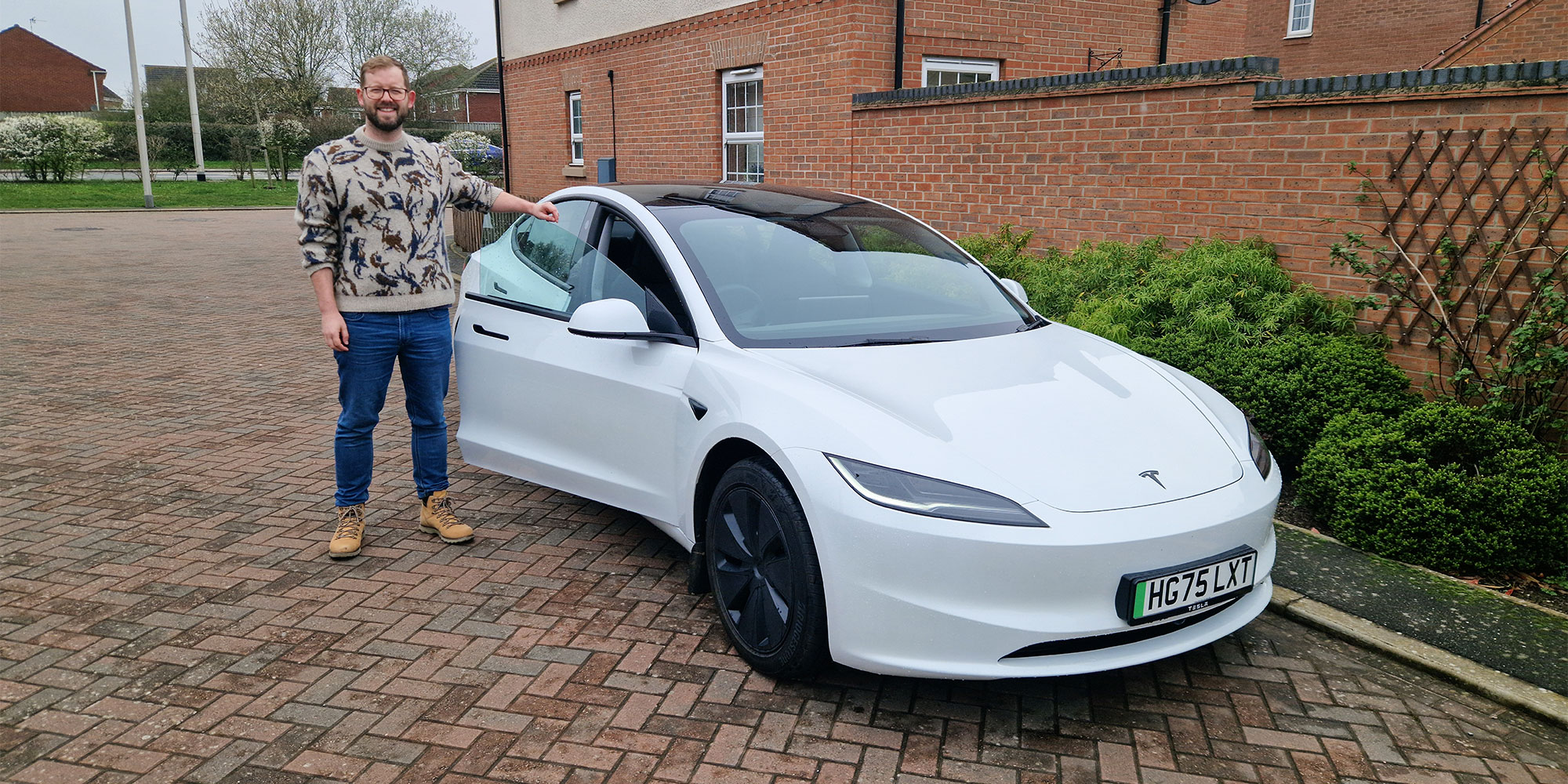 Which? scientific advisor Neal Rimmer standing next to a white Tesla Model 3 on a driveway.