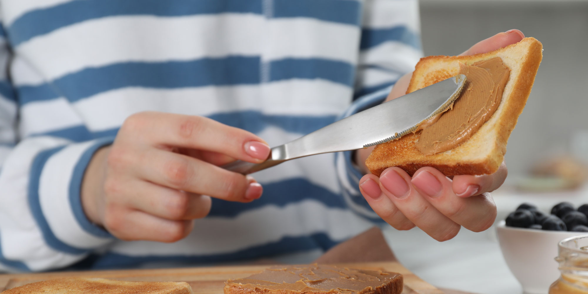 Close up of person spreading peanut butter onto toast