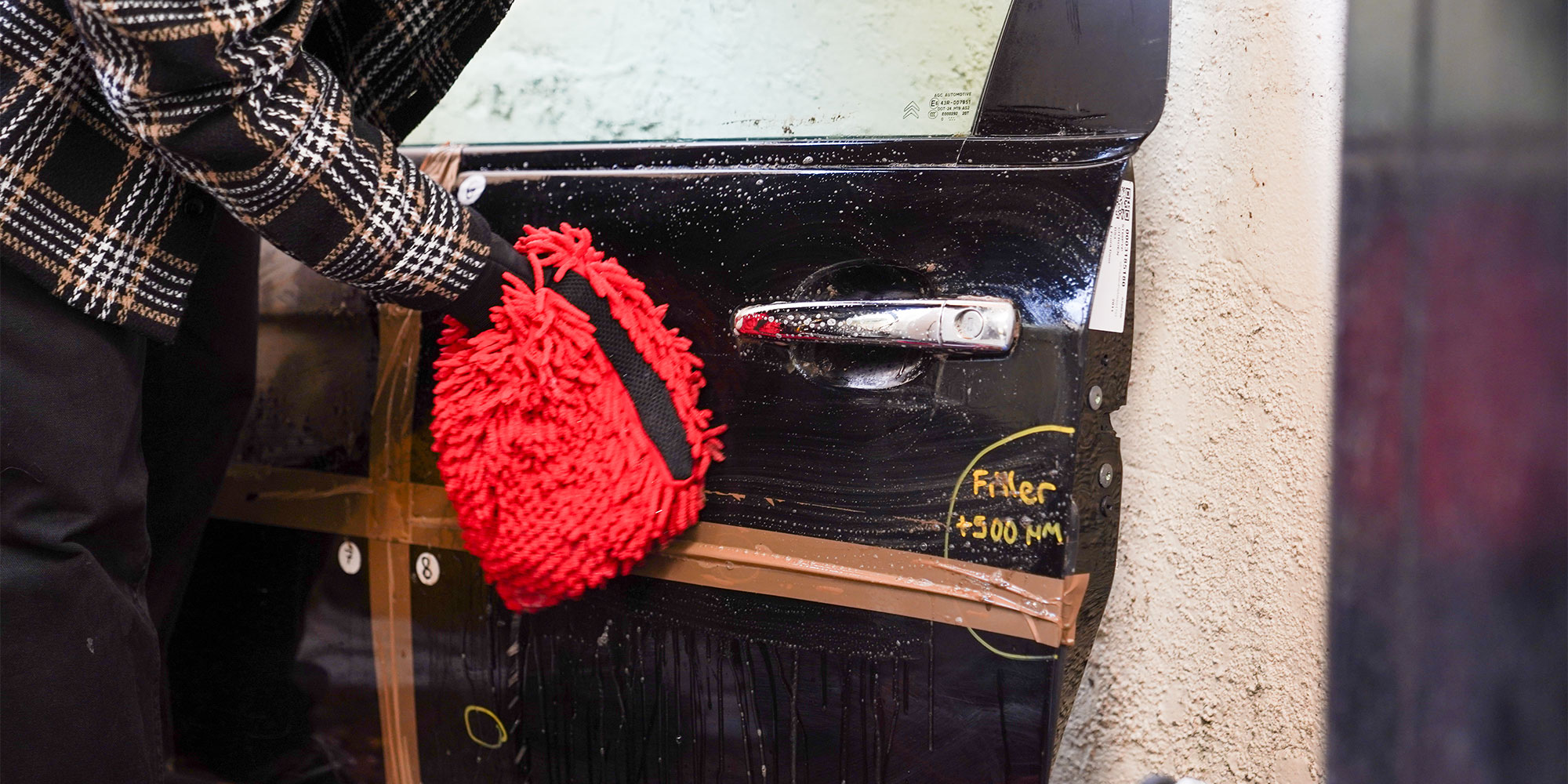The car cleaning expert wiping mud away with a wash mit.