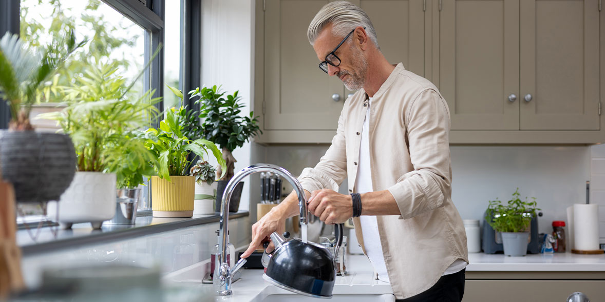 Man filling a kettle in a kitchen