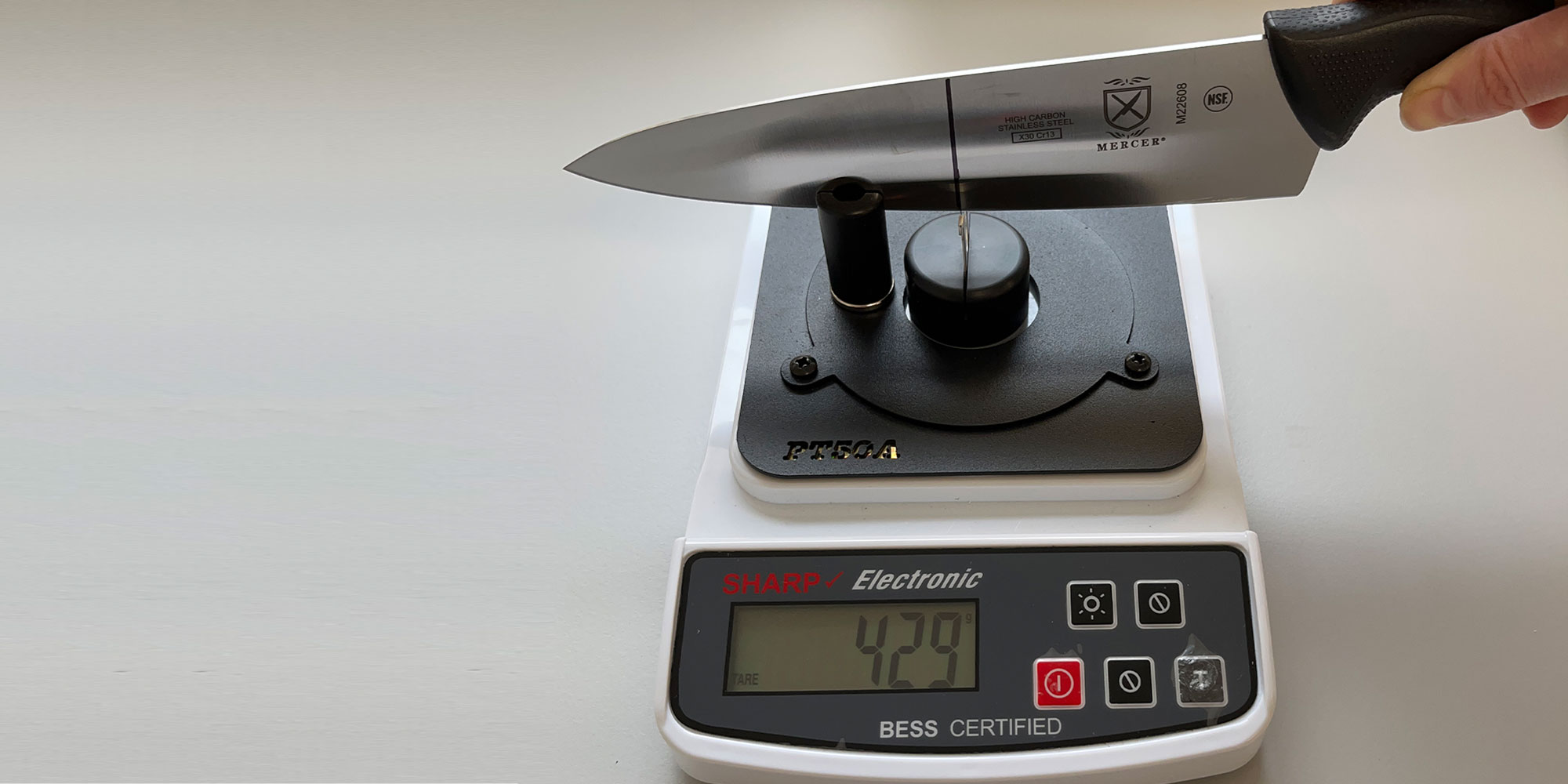 Testing image showing the sharpness tool being used to measure the sharpness in grams of a kitchen knife. 