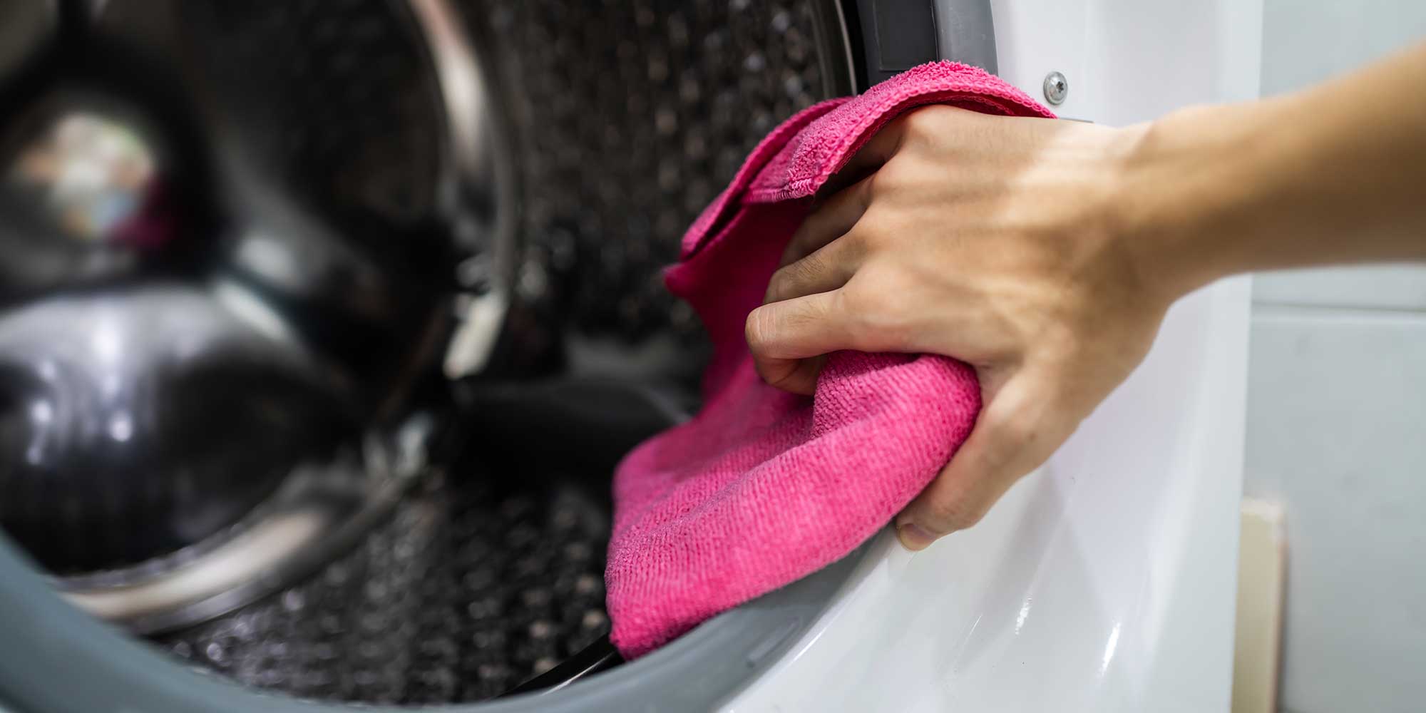 Person wiping the inside of a washing machine