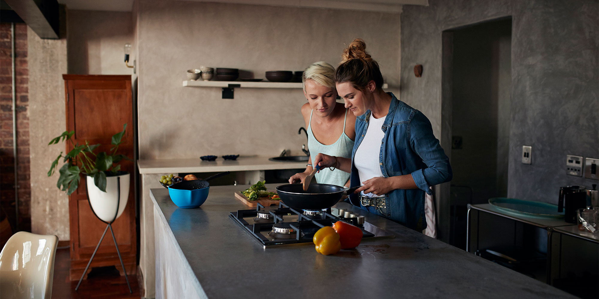 Two people cooking at an island unit gas hob