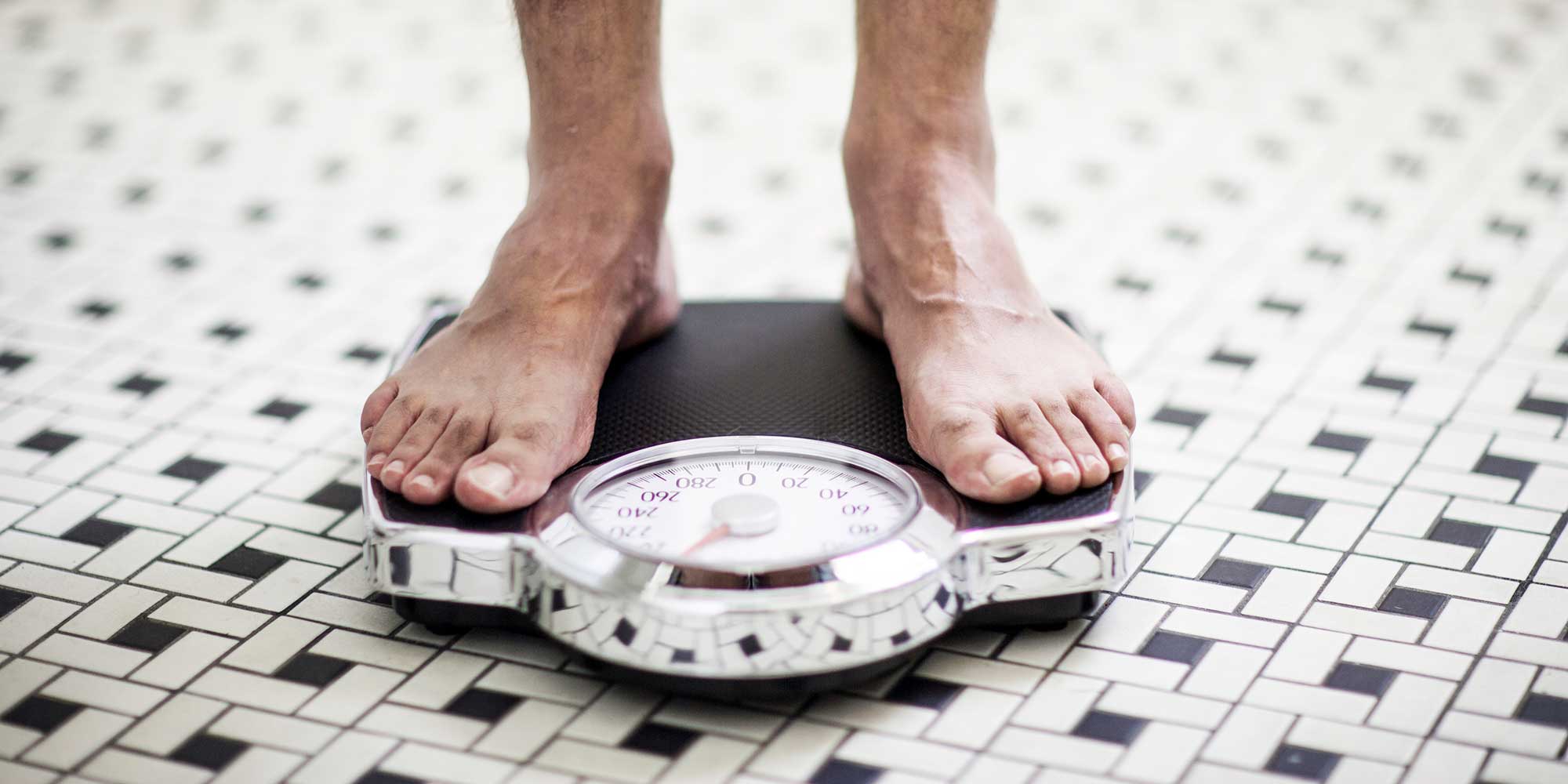 Person standing on bathroom scales weighing themselves