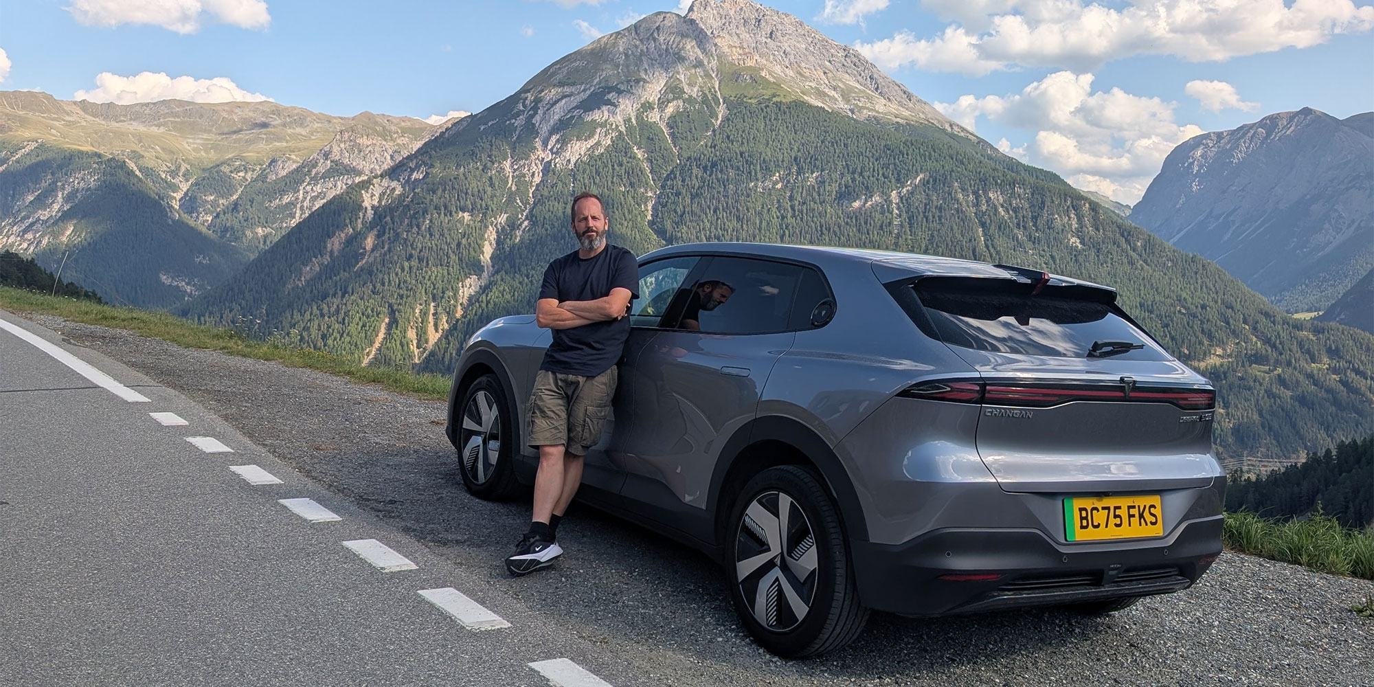 Person standing in front of a Changan Deepal S05 electric car with a mountain backdrop