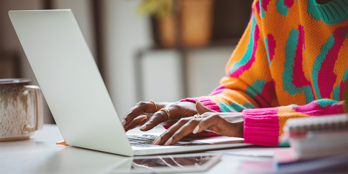 A person sitting at a table typing on a laptop