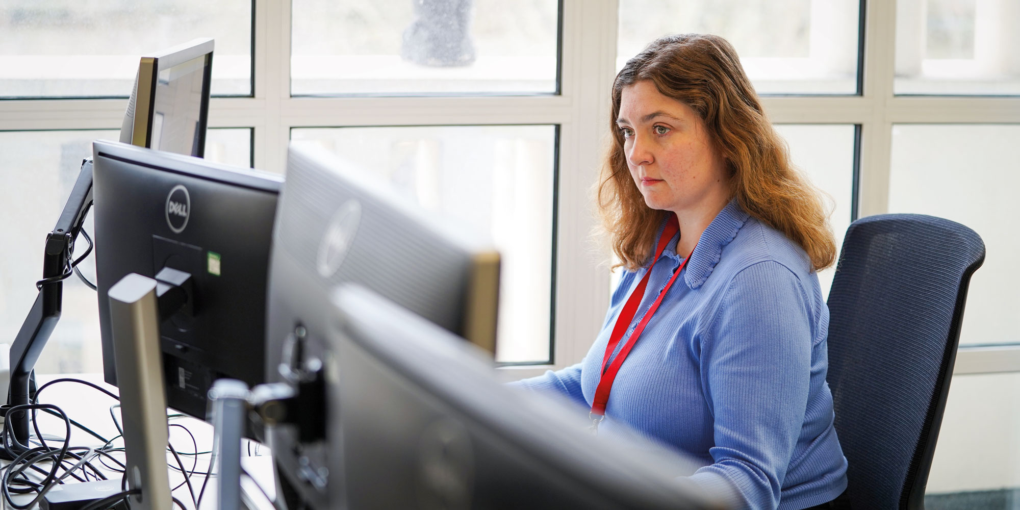 Which? investigative journalist Faye Lipson sits at a desk looking intently at a computer screen.