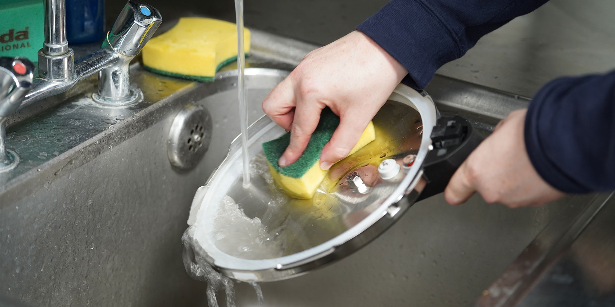 Cleaning a pressure cooker's lid under a tap