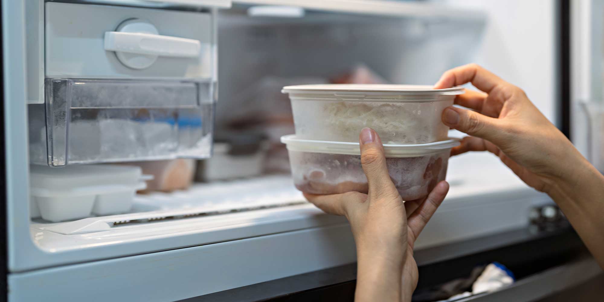 A person putting leftover food into the freezer