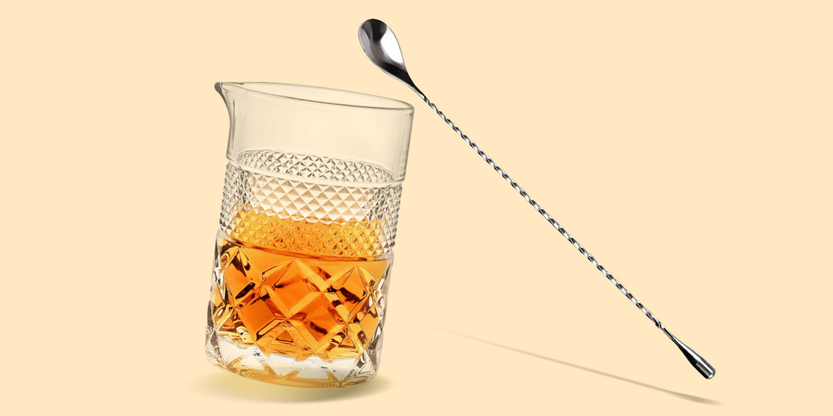 a cocktail mixing glass and bar spoon