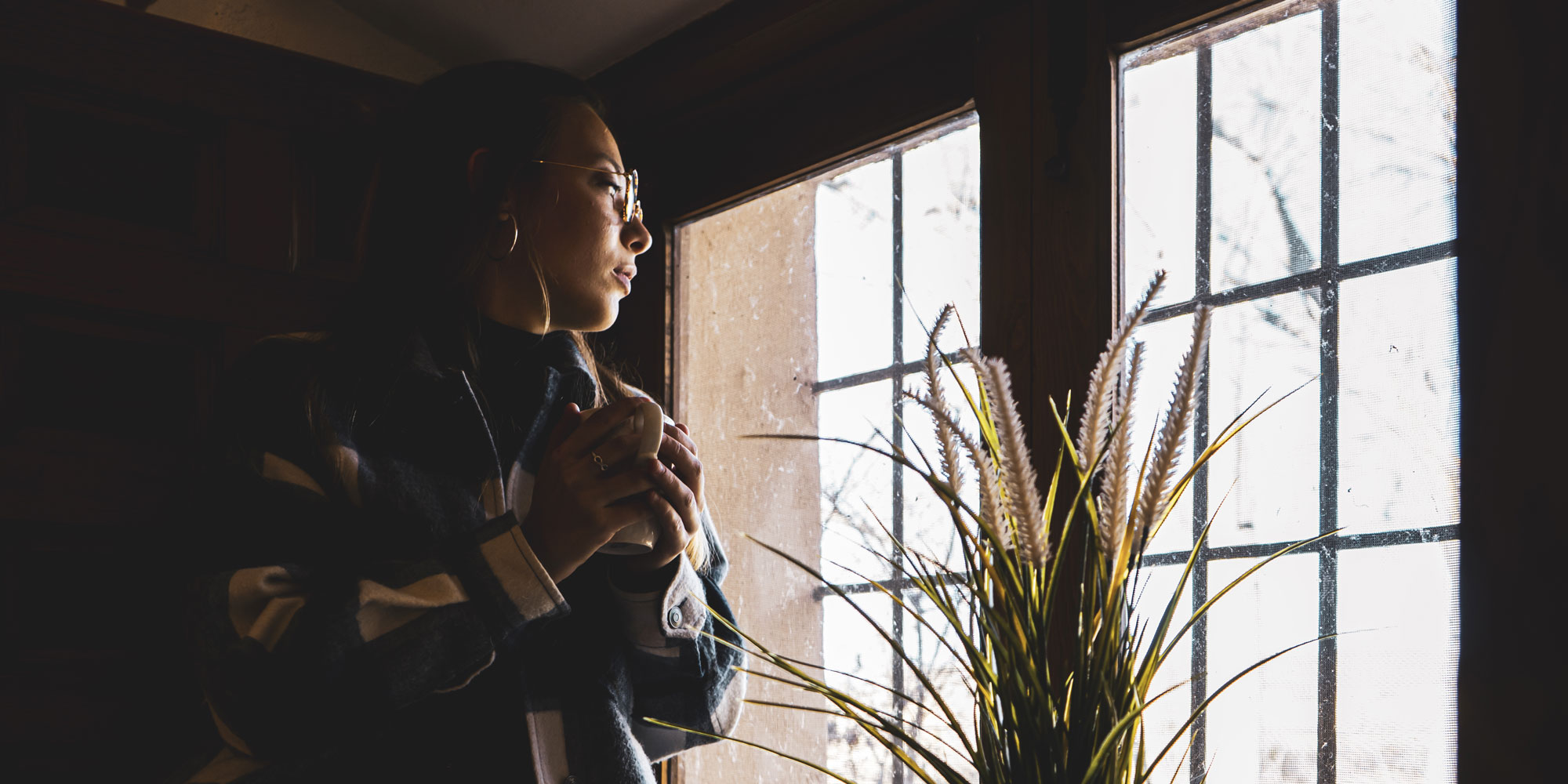 A woman in a dark room looking out of the window