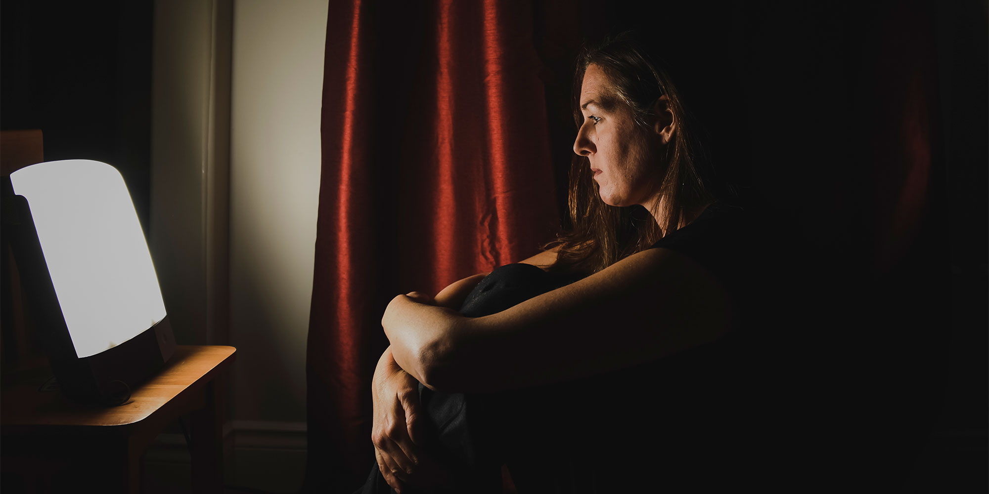 A woman resting in front of a SAD lamp