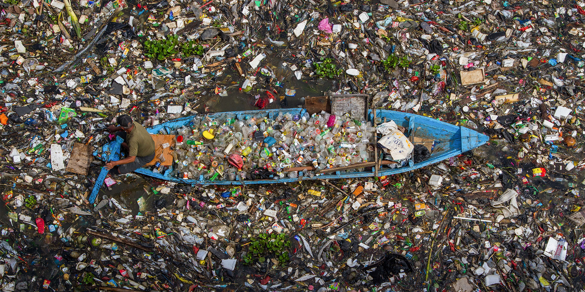 plastics in water surrounding small boat