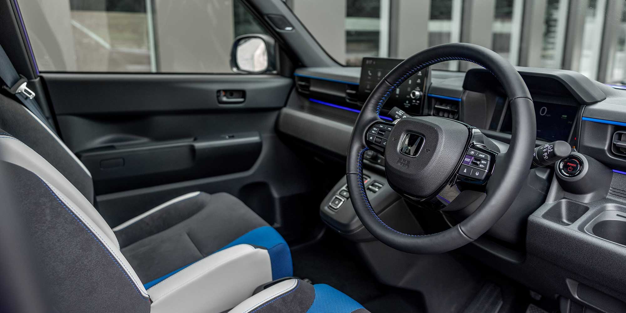 Interior of a Honda Super-N car with black and blue seats, steering wheel, and dashboard.