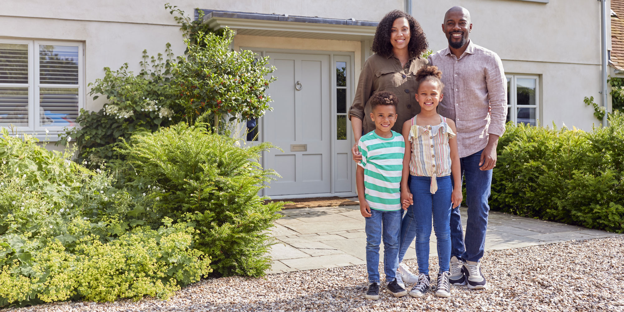 Family of four standing outside a house