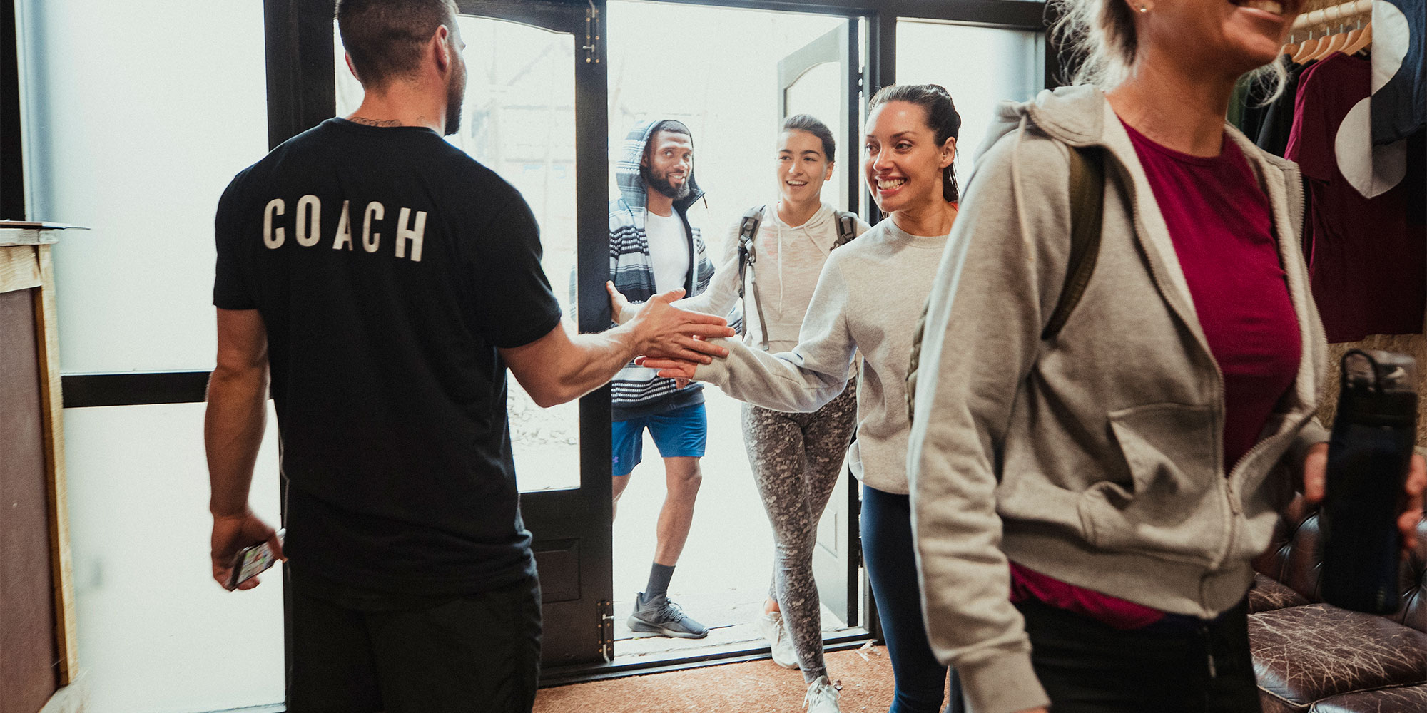 woman joining the gym high fiving the coach when entering class