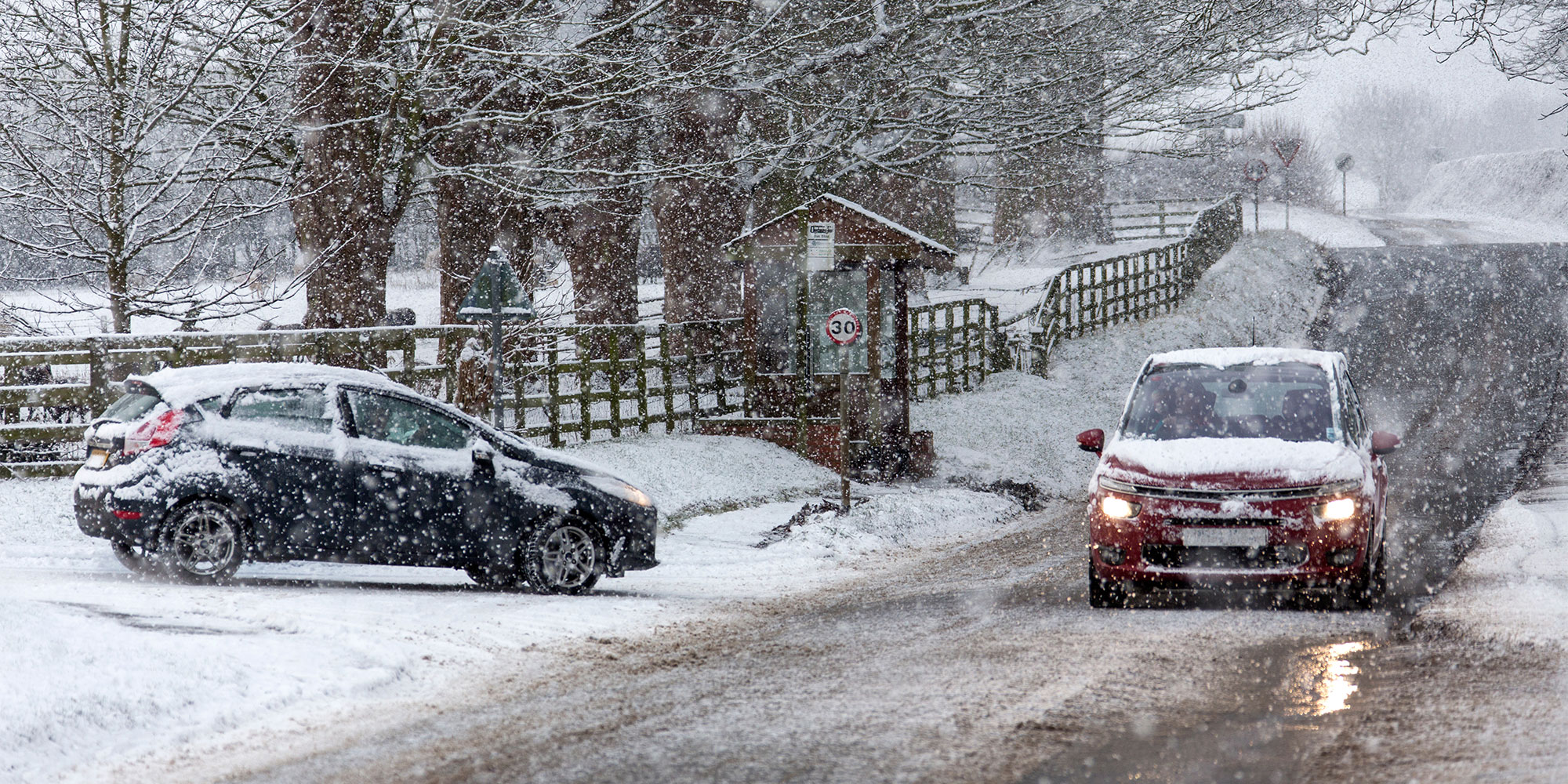 Two cars on a country road with heavy snow falling