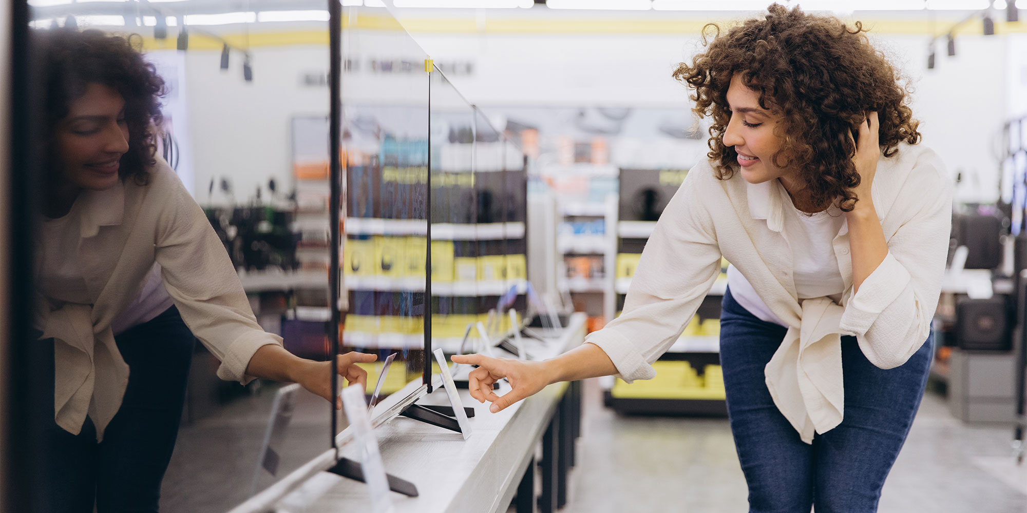 A woman is checking the ticket for a TV in a showroom