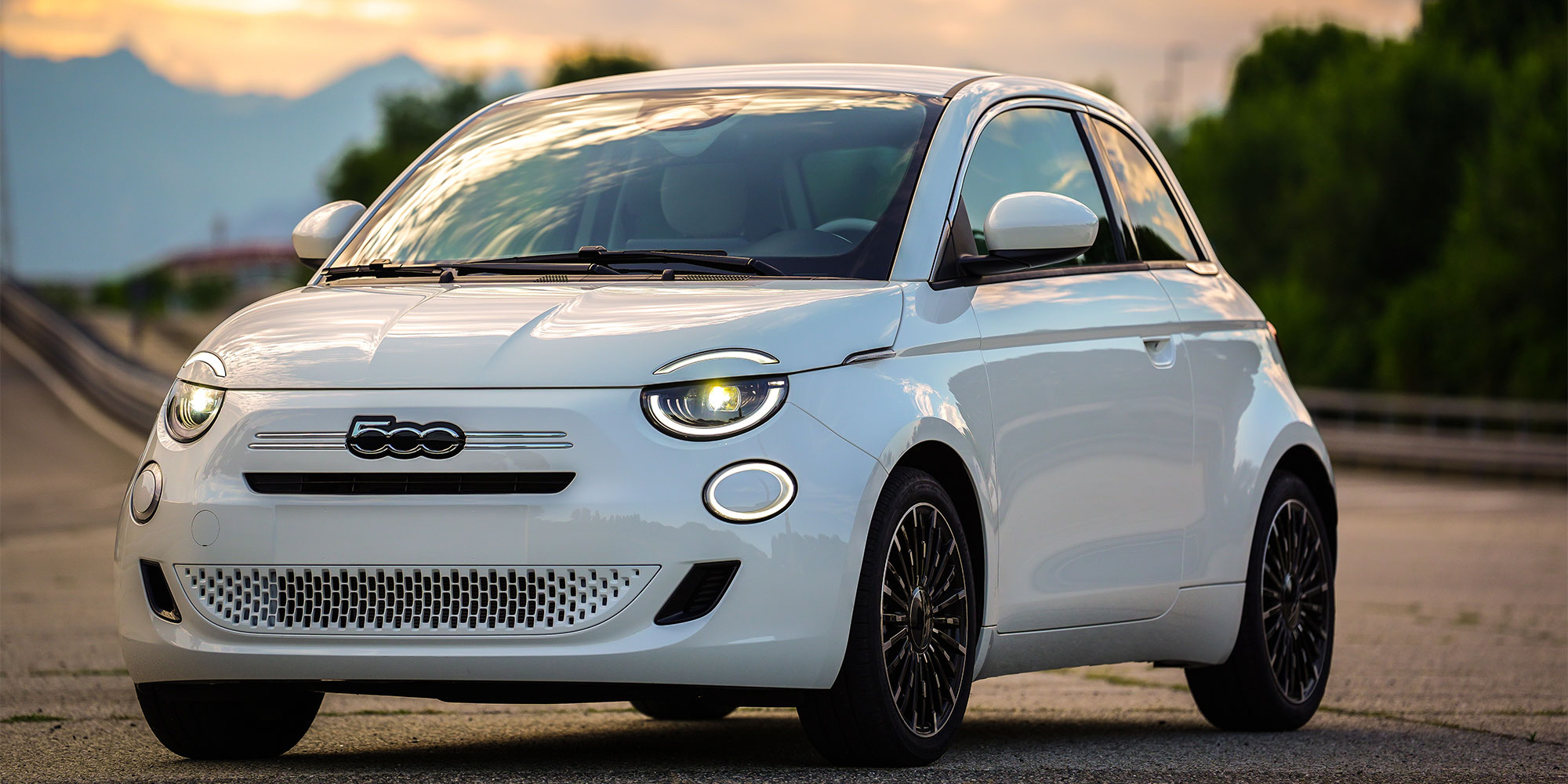 A white Fiat 500, parked on a road
