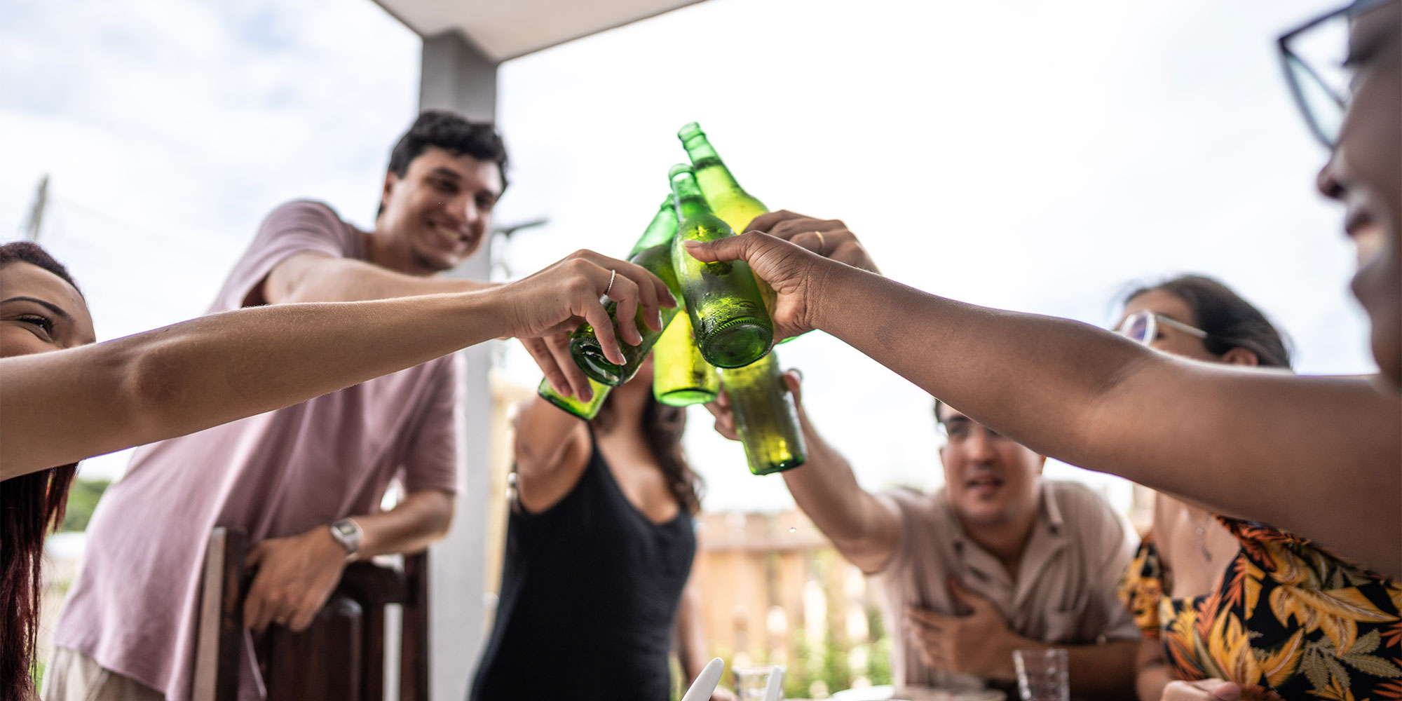 A group of people clinking bottles of beer