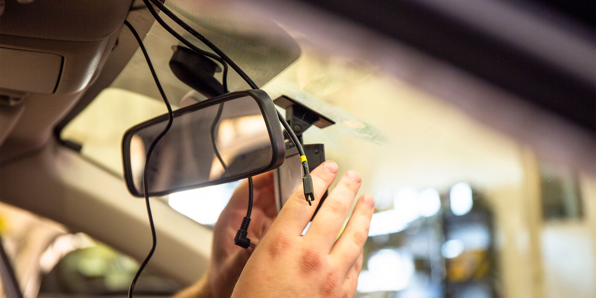 A person installing a dash cam in a car