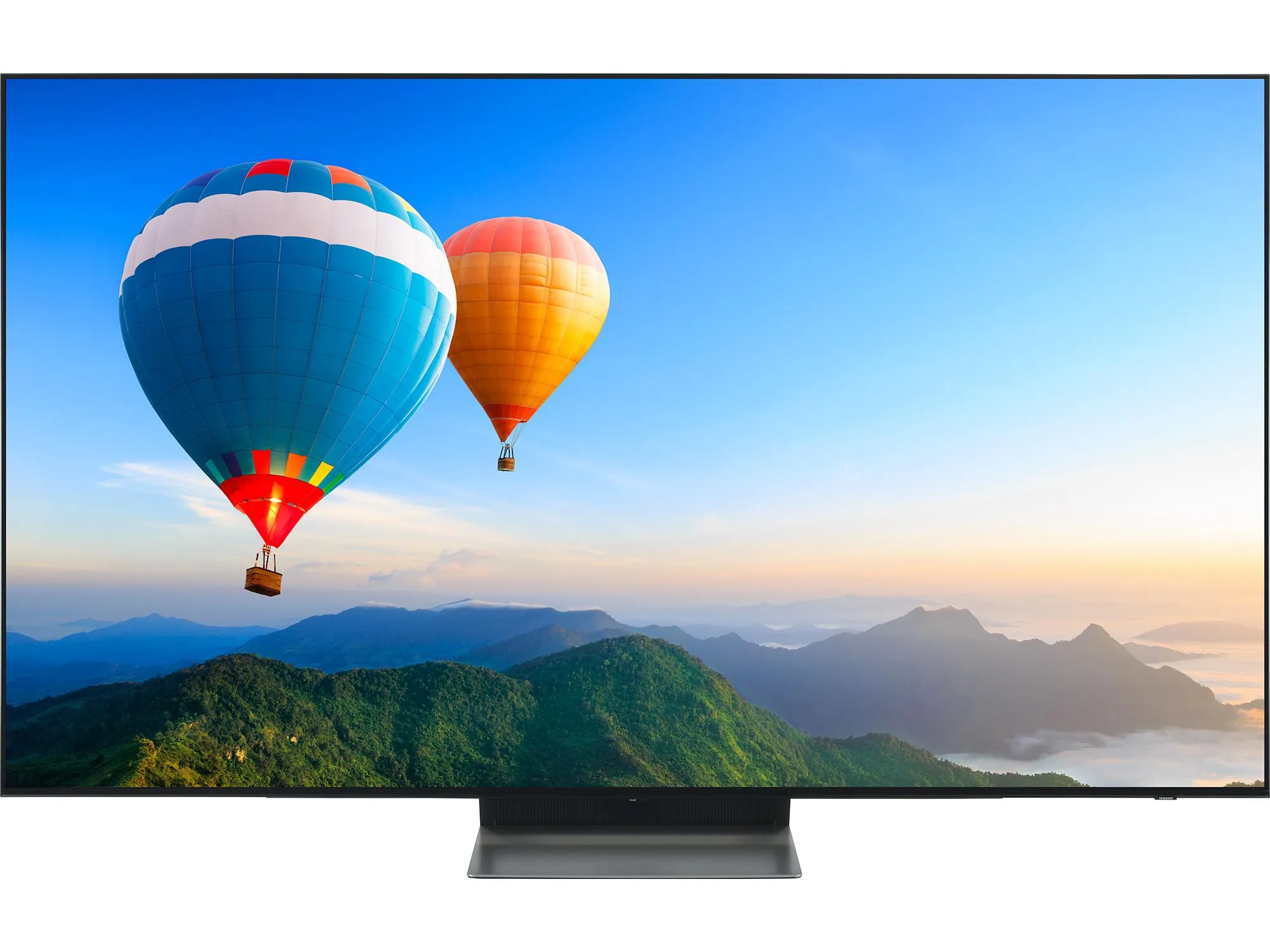 A black TV with a narrow rectangular stand displaying two hot air balloons floating over a forested mountain range