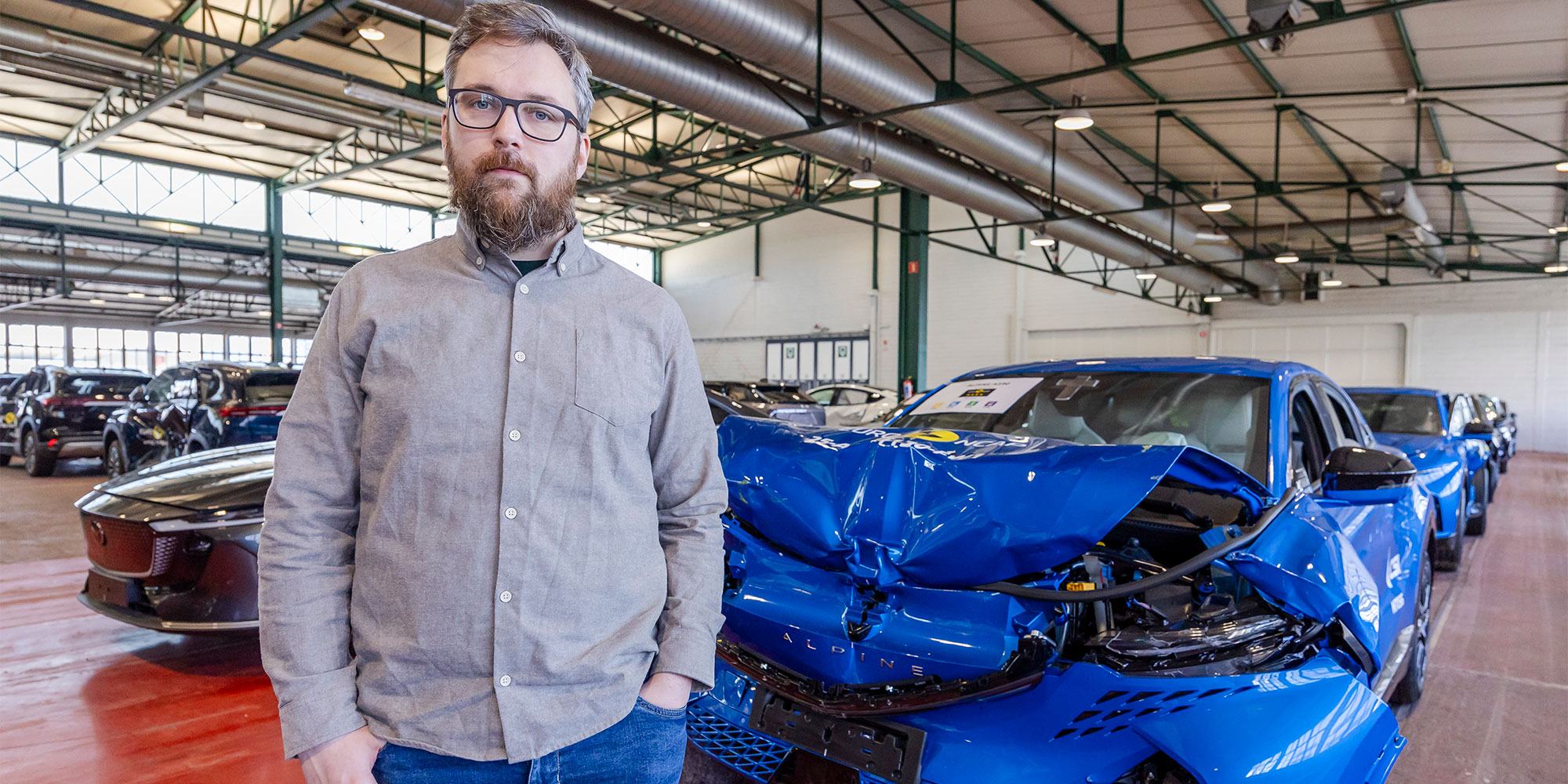 Man standing in front of blue car after Euro NCAP crash test