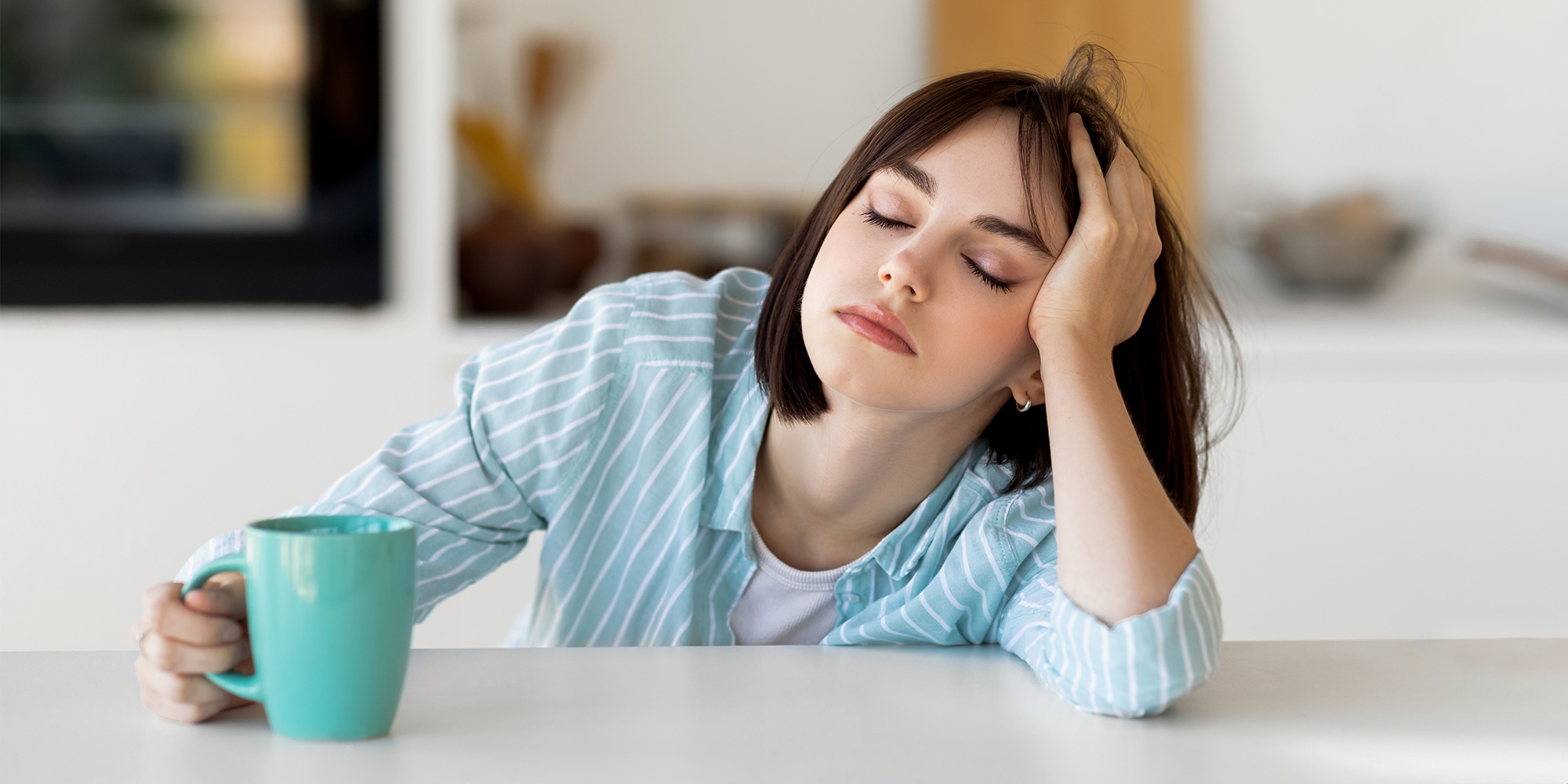 A woman looking tired slumped at a kitchen table