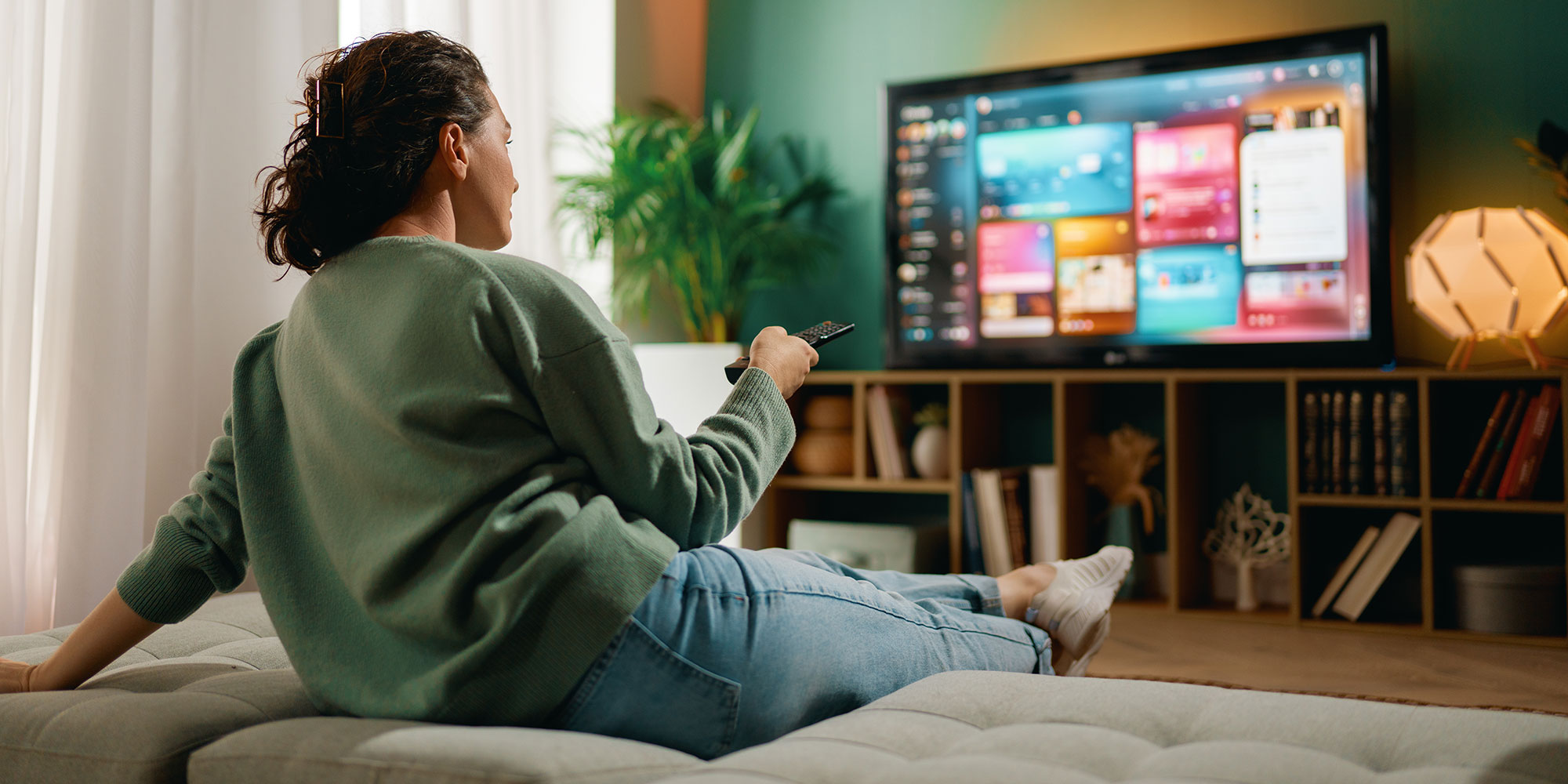 A woman is watching TV at home.