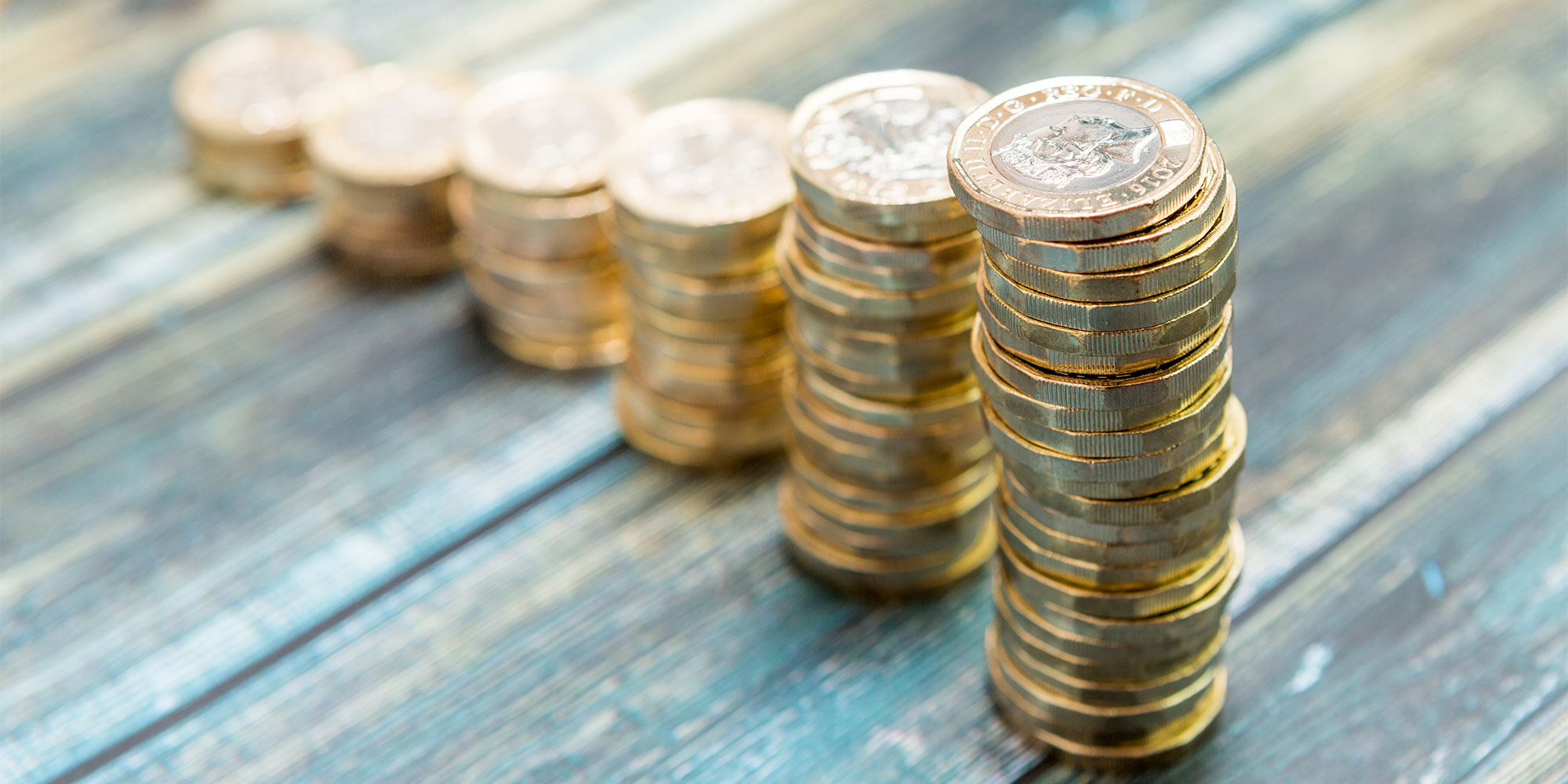 Six piles of coins on a table, in ascending order of height, with the nearest pile having the most coins.