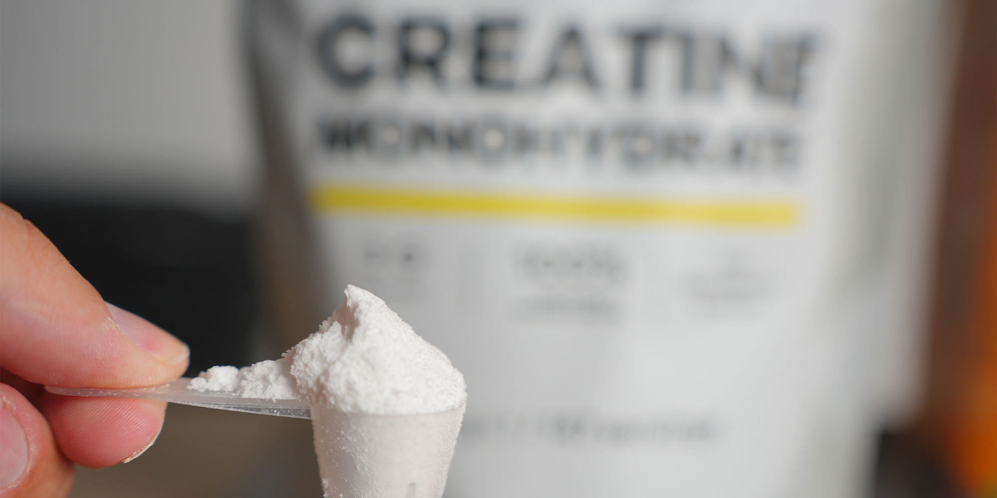 Creatine powder in a scoop with packet in the background