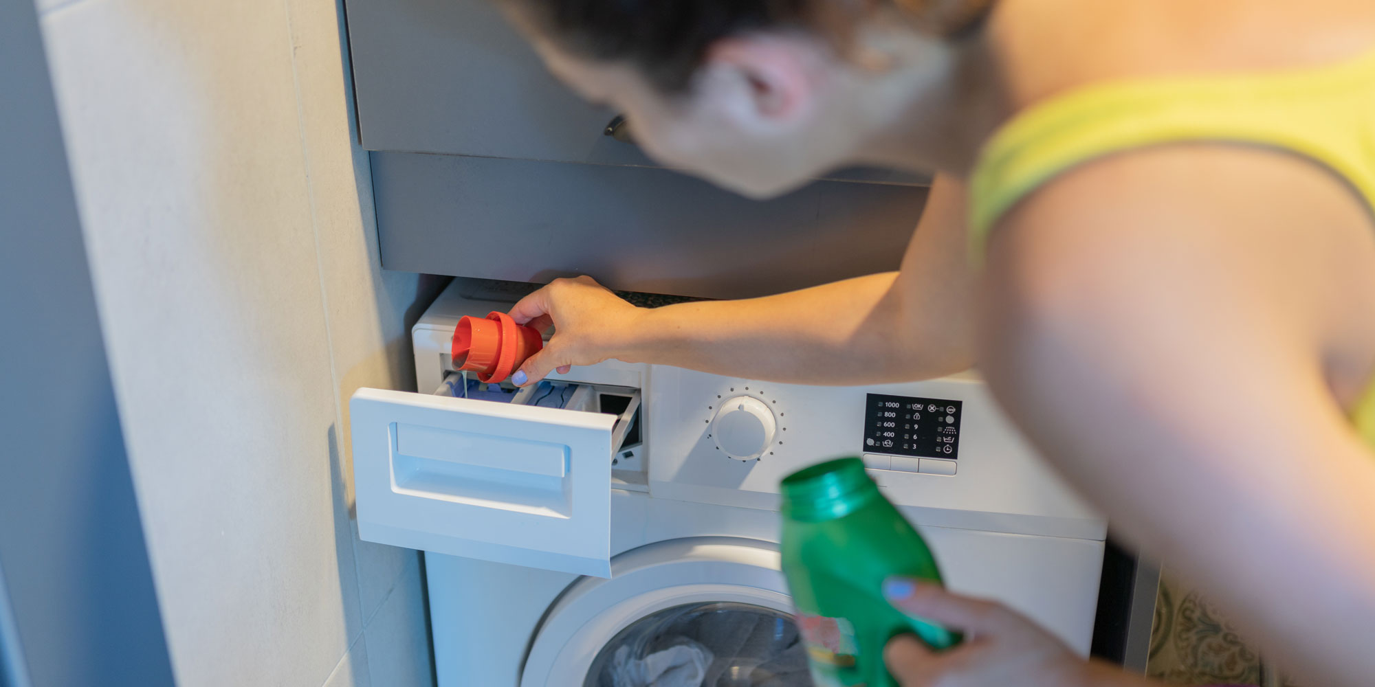 Person adding detergent to a washing machine