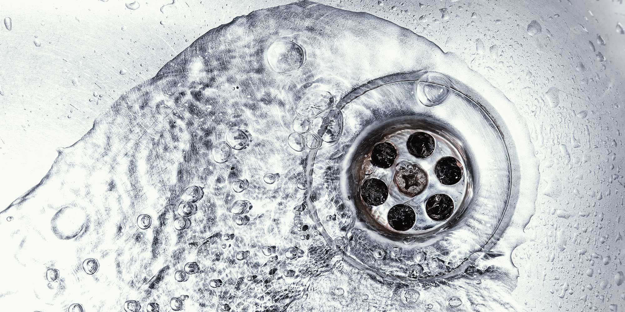 A stainless steel sink hole with water running down