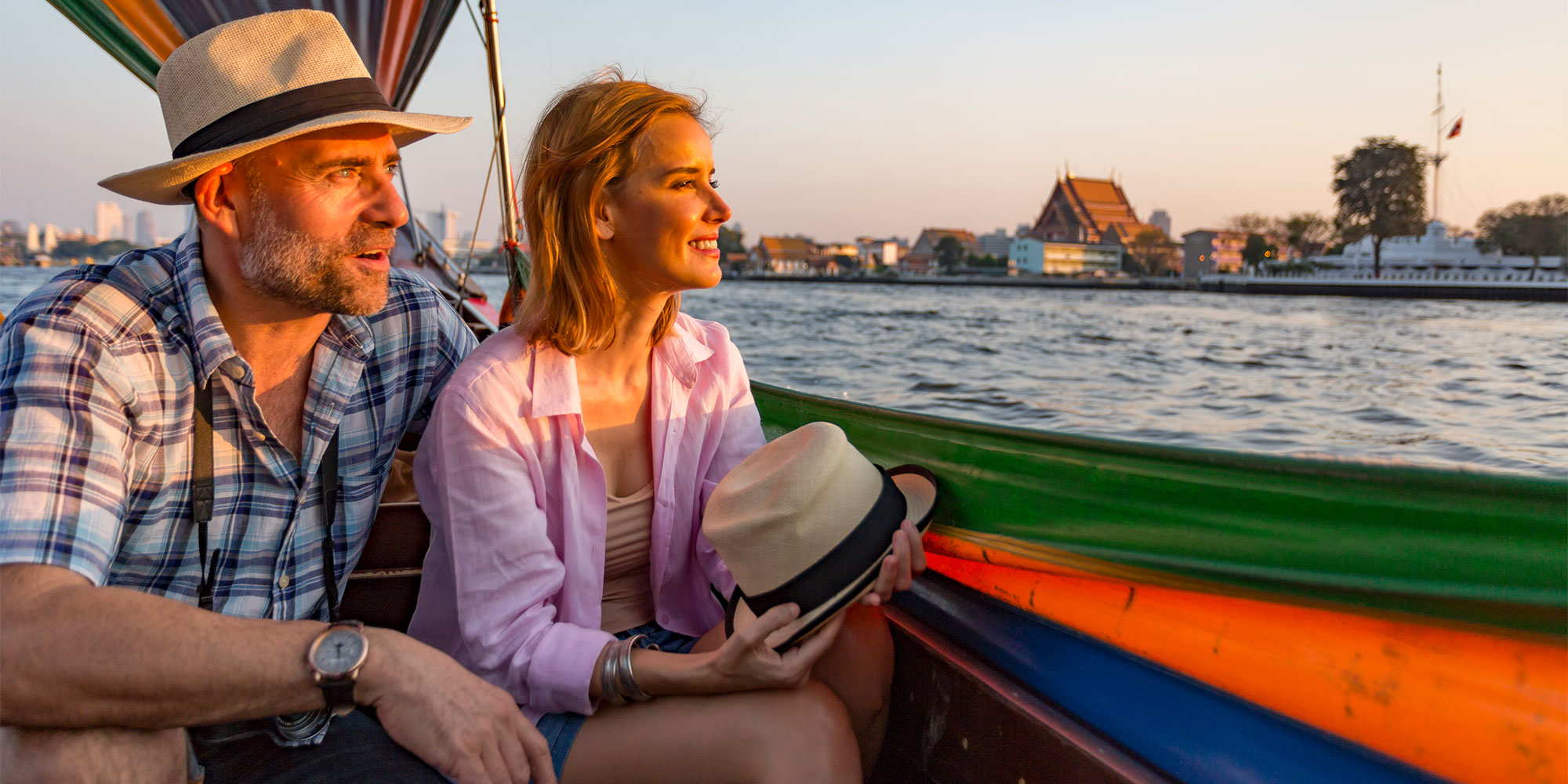 A travelling couple on holiday looking out from their boat at the riverside in Bangkok, Thailand